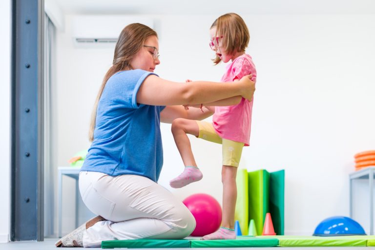 Support worker with young disabled girl doing aerobic exercise
