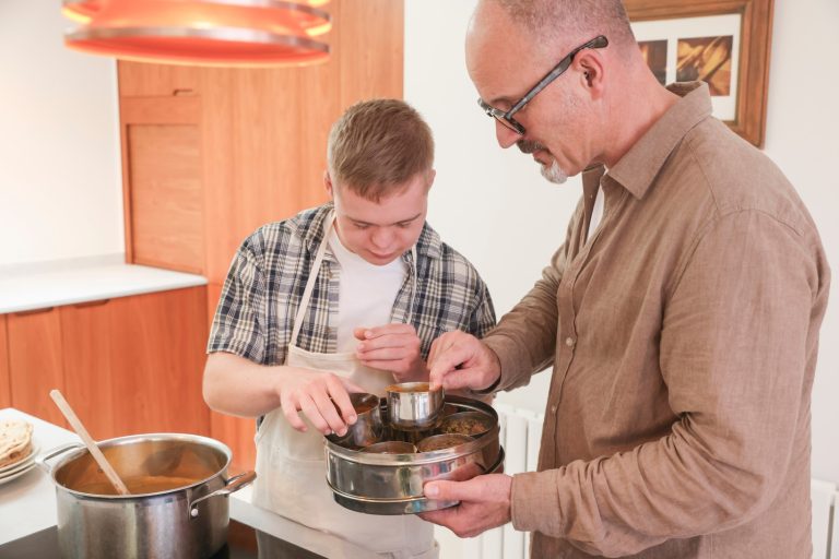 Disabled boy and carer cooking food in the kitchen