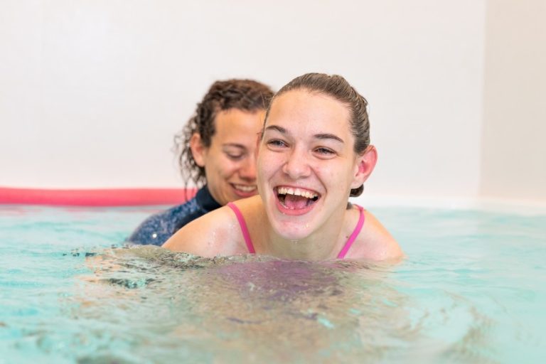 Disabled girl and carer participating in a swimming class