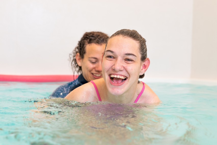 Disabled girl and carer participating in a swimming class