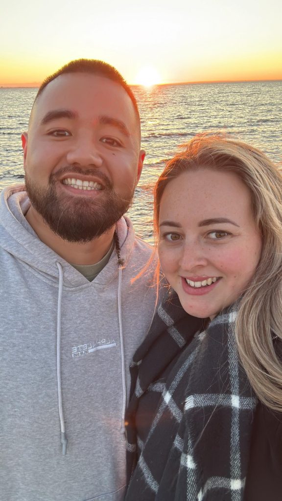 Both founders smiling at camera in front of a scenic ocean backdrop